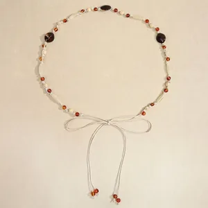 Detail of bohemian hand-woven belt featuring amber beads and cream adjustable cords