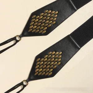 Macro shot of vintage black leather belt featuring bronze leaf rivets and braided cord
