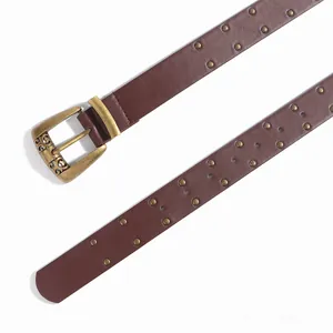 Détail d'une ceinture en cuir marron vintage avec clous en laiton et boucle gravée
