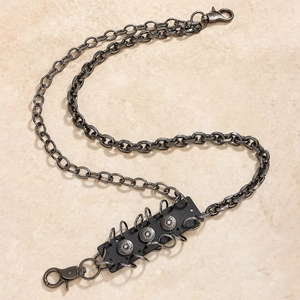 Macro detail of punk style gunmetal trouser chain with leather patch and metal rivets