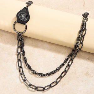 Detail of punk style layered black metal pants chain with leather pendant and ring