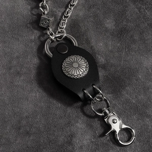 Vue macro de la chaîne industrielle avec pendentif dé et sangle en cuir noir concho