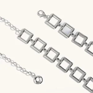 Detail of silver square link chain with lobster clasp and round pendant on white background