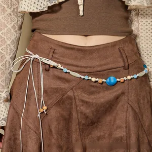 Close-up of Bohemian braided waist rope with blue beads and tassels on a suede skirt