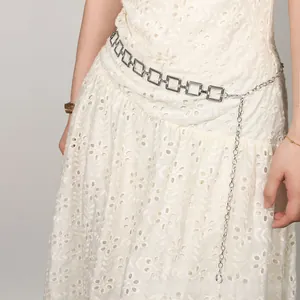 Detailed silver square chain belt with hanging fringe on a white embroidered dress