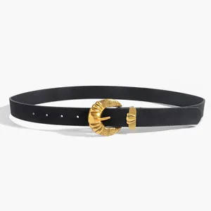 Détail d'une ceinture vintage noire en PU avec boucle dorée en croissant à motifs ciselés