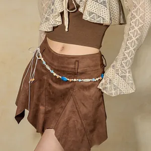Detail of bohemian brown suede skirt featuring colorful bead accents and ethnic fringe