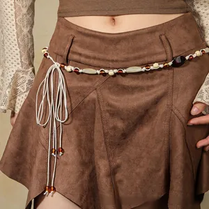 Detail of bohemian braided waist rope with amber beads and tassels on a suede skirt