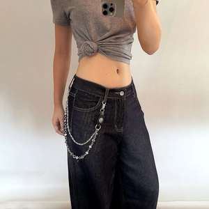 Détail d'un jean taille haute street style avec double chaîne de taille à dés argentée