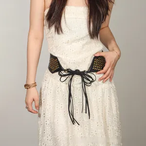 Detail of black faux leather waist belt with gold studs and long fringe tassels