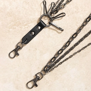 Detail of multi-layer gunmetal chains with black leather rivet accents and hooks