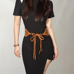 Detail view of brown suede waist belt with gold rivets and lace-up strap on black dress