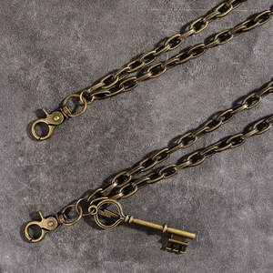 Détail macro d'une chaîne de pantalon bronze rétro avec mousquetons et pendentif clé