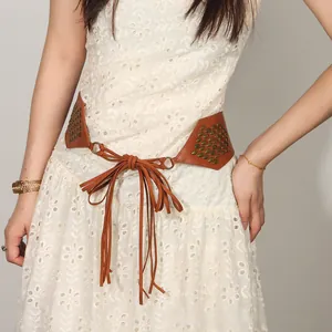 Close-up of brown suede belt with metal rivets and long tassels on white lace dress