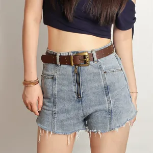 Détail de la ceinture vintage en PU marron avec clous dorés sur un short en jean bleu