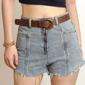 Détail d'une ceinture vintage en PU avec boucle dorée sur un short en jean bleu clair