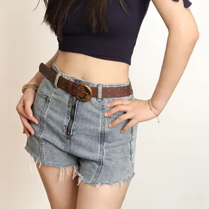 Détail d'une ceinture vintage en cuir PU marron avec rivets en laiton sur un short