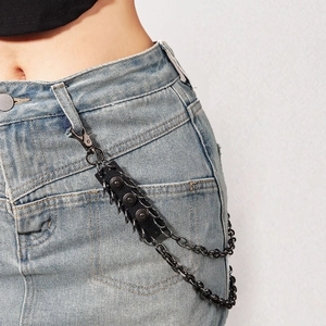 Detail of punk style black metal waist chain with rivet leather strap on denim skirt
