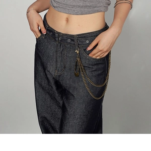 Detail of high-waist denim jeans with punk double metal chains and safety pin charms