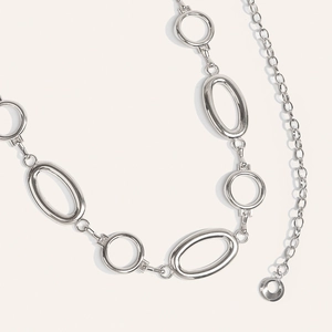 Close-up of polished silver metal chain belt featuring interlocking oval and round links