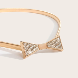 Detail of gold metal spring belt with a crystal-encrusted bow buckle for dresses
