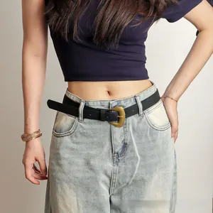 Détail d'une ceinture en cuir PU noir avec boucle en bronze sur un jean clair délavé