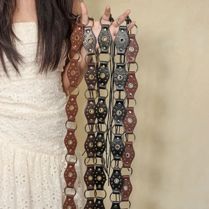 Macro view of vintage leather belt featuring metal rings and rivet studs on brown panels