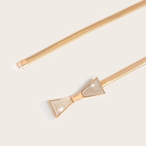 Close-up of golden elastic metal belt featuring a sparkling rhinestone butterfly buckle