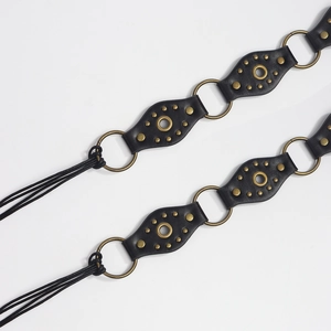 Detail of vintage black leather belt with metal eyelets and bronze ring links on white back