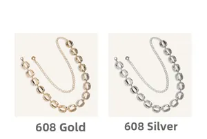 Detailweergave van de taillekettingen met grote ovale schakels in goud en zilver