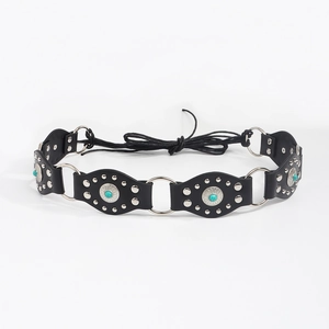Détail d'une ceinture bohème avec ovales en cuir noir, perles turquoise et rivets argentés