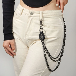 Detail of multi-layer punk pant chain with vintage leather badge and black metal hooks