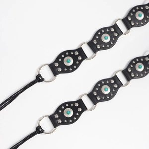 Détail d'une ceinture bohème avec motifs concho argentés et incrustations turquoises