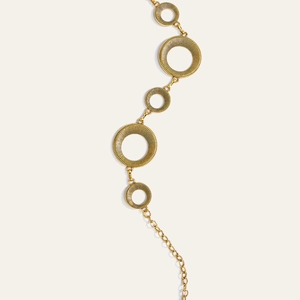 Macro-opname van gouden geometrische ringen met radiale textuur aan een metalen lichaamsketting