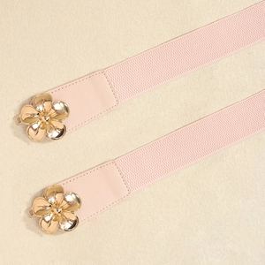 Detailaufnahme der goldenen Blumenschnalle am rosa elastischen Gürtel für Kleider