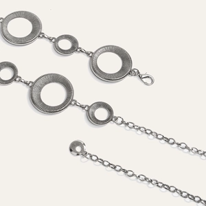 Detail van zilveren lichaamsketting met getextureerde geometrische ringen en sluiting