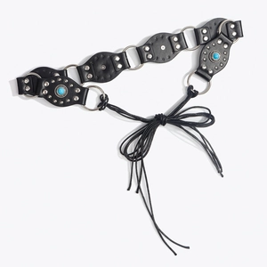 Détail de ceinture bohème avec rivets argentés, pierres bleues et anneaux métalliques reliés