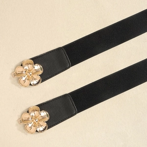 Detail eines schwarzen elastischen Gürtels mit eleganter goldener Blumenschnalle