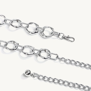 Detail van zilveren geometrische tailleketting met onregelmatige ringen en karabijnhaak