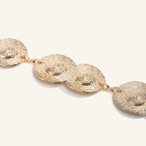 Dettaglio della catena dorata in vita con maglie a spirale strutturate e anelli metallici