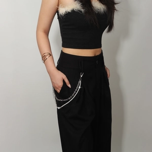 Detail of silver double-layered rhinestone waist chain on black high-waisted wide-leg trousers