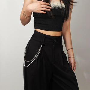 Detail of silver multi-layer metal chain on high-waist black wide-leg trousers
