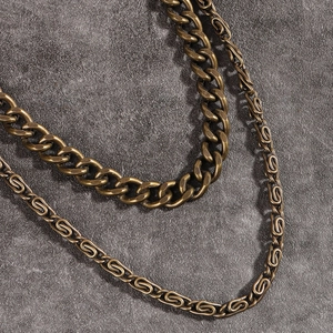 Detail of double-layer punk style bronze metal pants chains on a textured stone surface