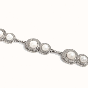 Macro shot of silver alloy belt chain with textured circular links and white pearl inlays