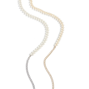 Detail of elegant pearl and metal chain belts in gold and silver finishes on white background