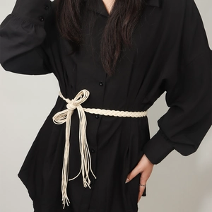 Detail eines cremefarbenen geflochtenen Seilgürtels mit langen Quasten am Hemdkleid