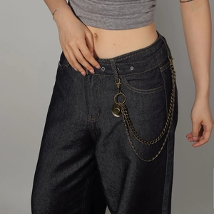 Detail of double-layer bronze metal chains on dark blue wide-leg high-waisted denim jeans