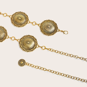 Détail d'une chaîne de taille vintage en métal doré avec médailles soleil et fermoir mousqueton