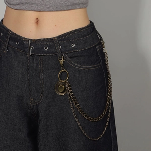 Detail of double-layered punk metal pants chain with cowboy hat pendant on denim