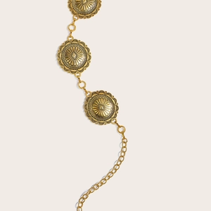 Détail de la ceinture chaîne en métal doré vintage avec des pendentifs floraux en relief